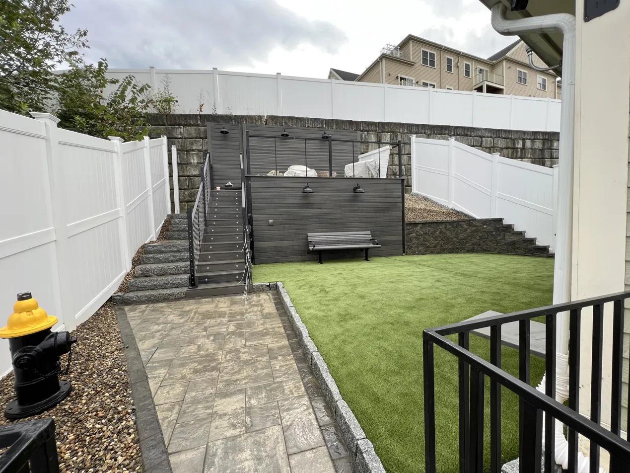 Finished stone paver patio with turf lawn and retaining wall